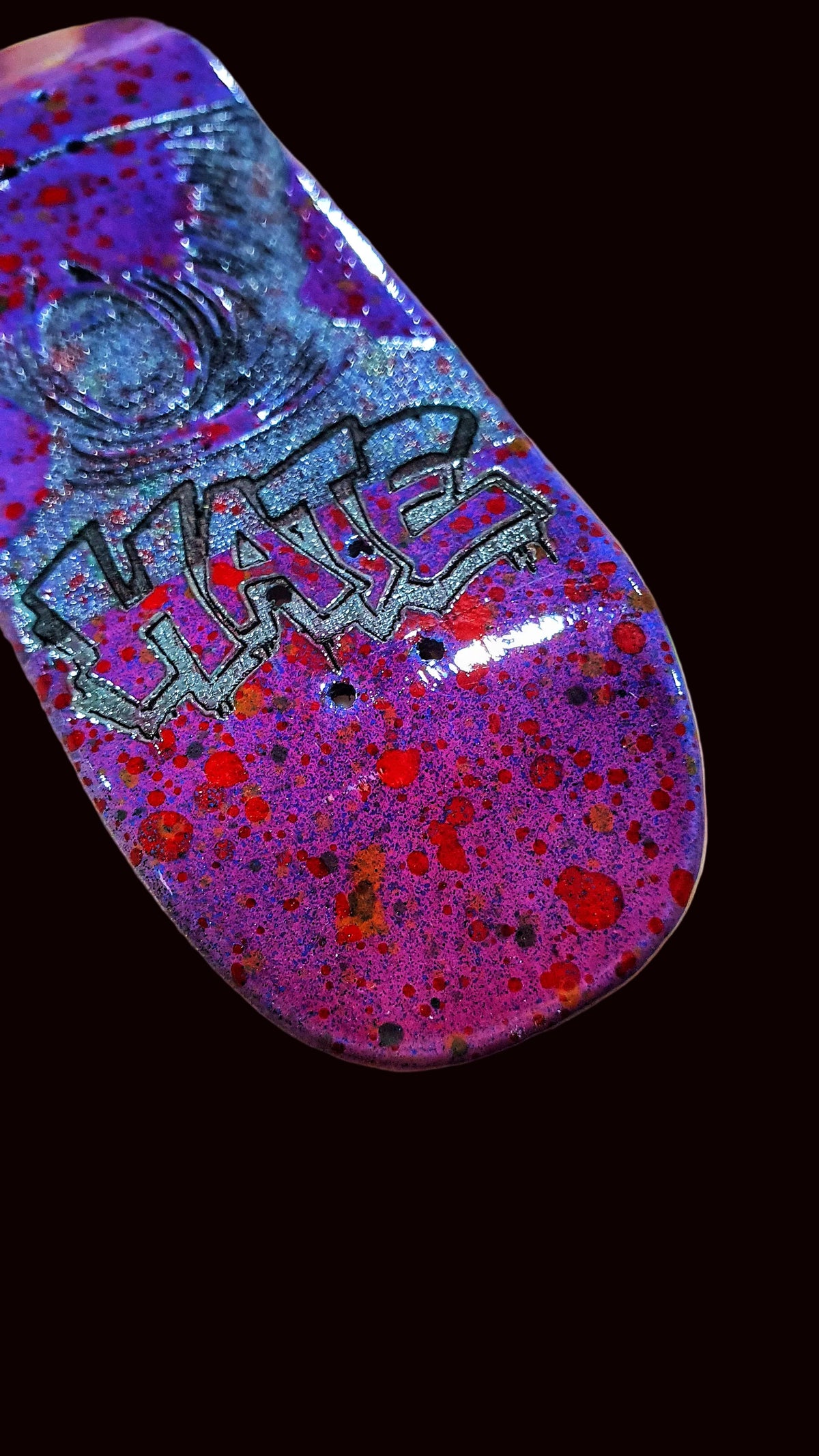 Purple fingerboard deck angled view showing bold 'HATE' graphic over splatter.
