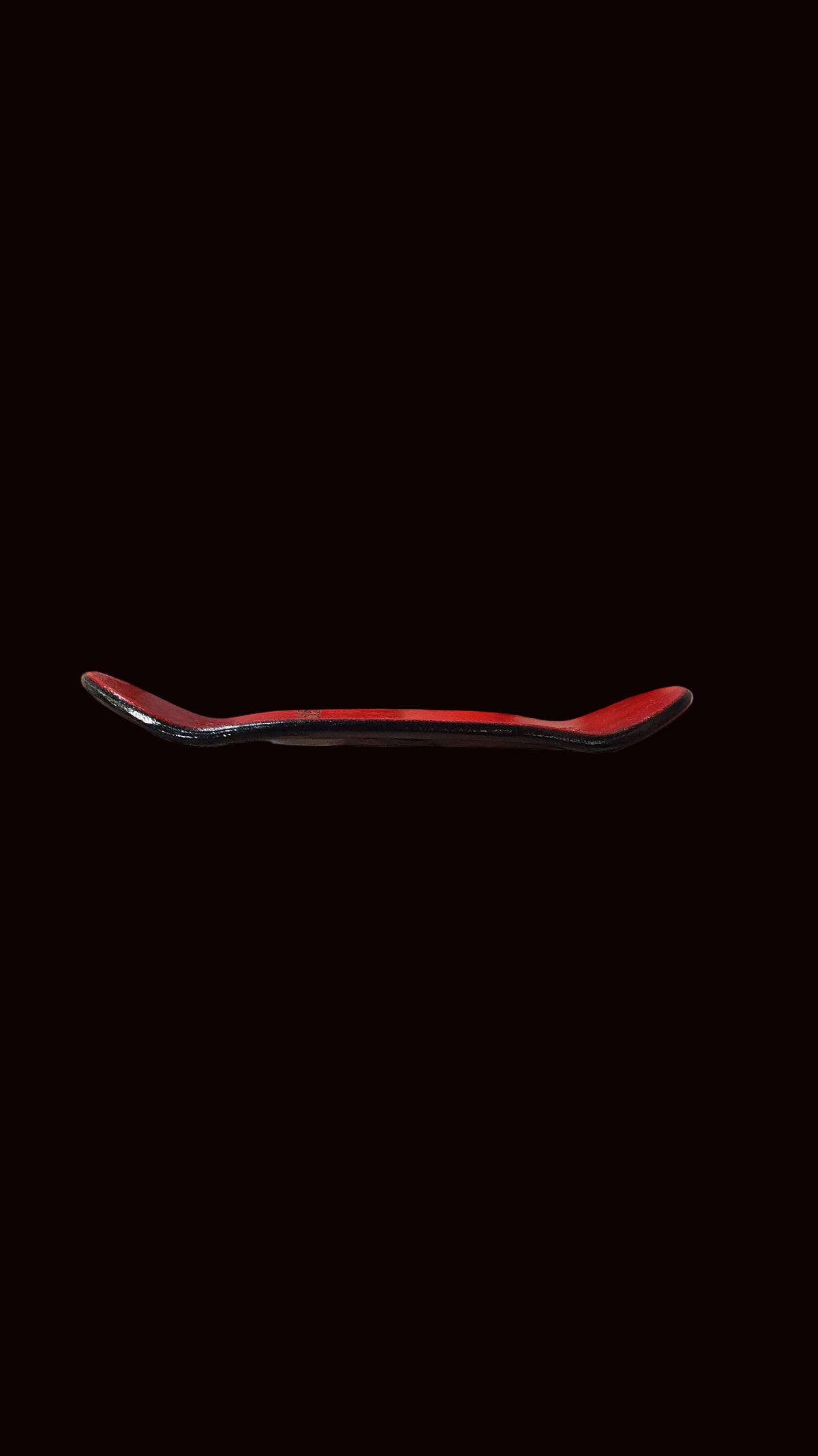 Skateboard deck with red top accent and dark underside, side profile view.