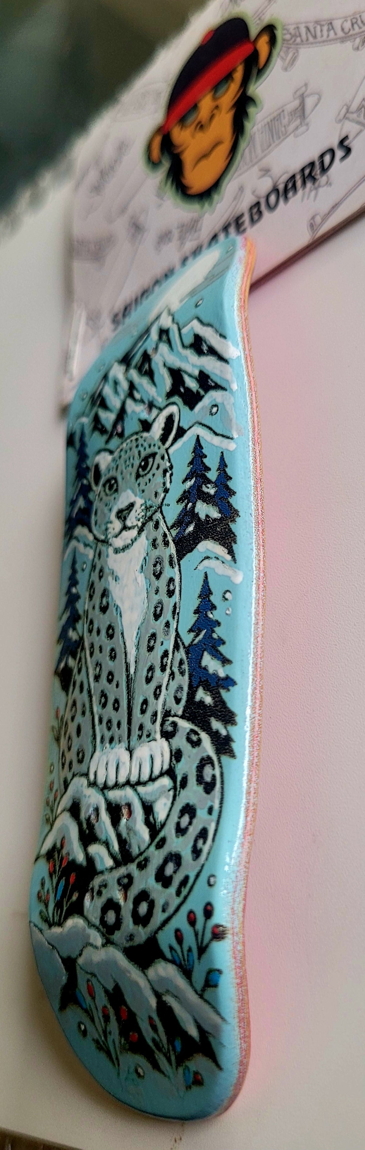 Teal finger skateboard deck side with snow leopard and forest artwork
