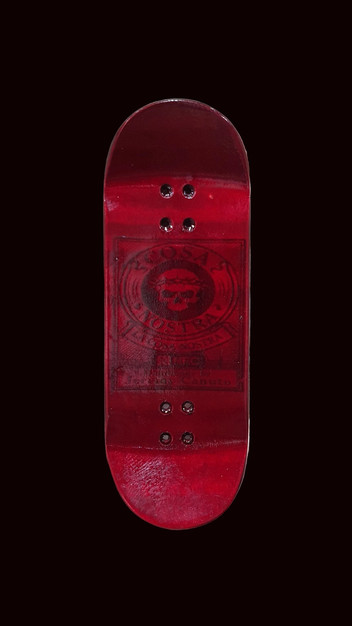 Red fingerboard deck with black skull logo and four bolt holes