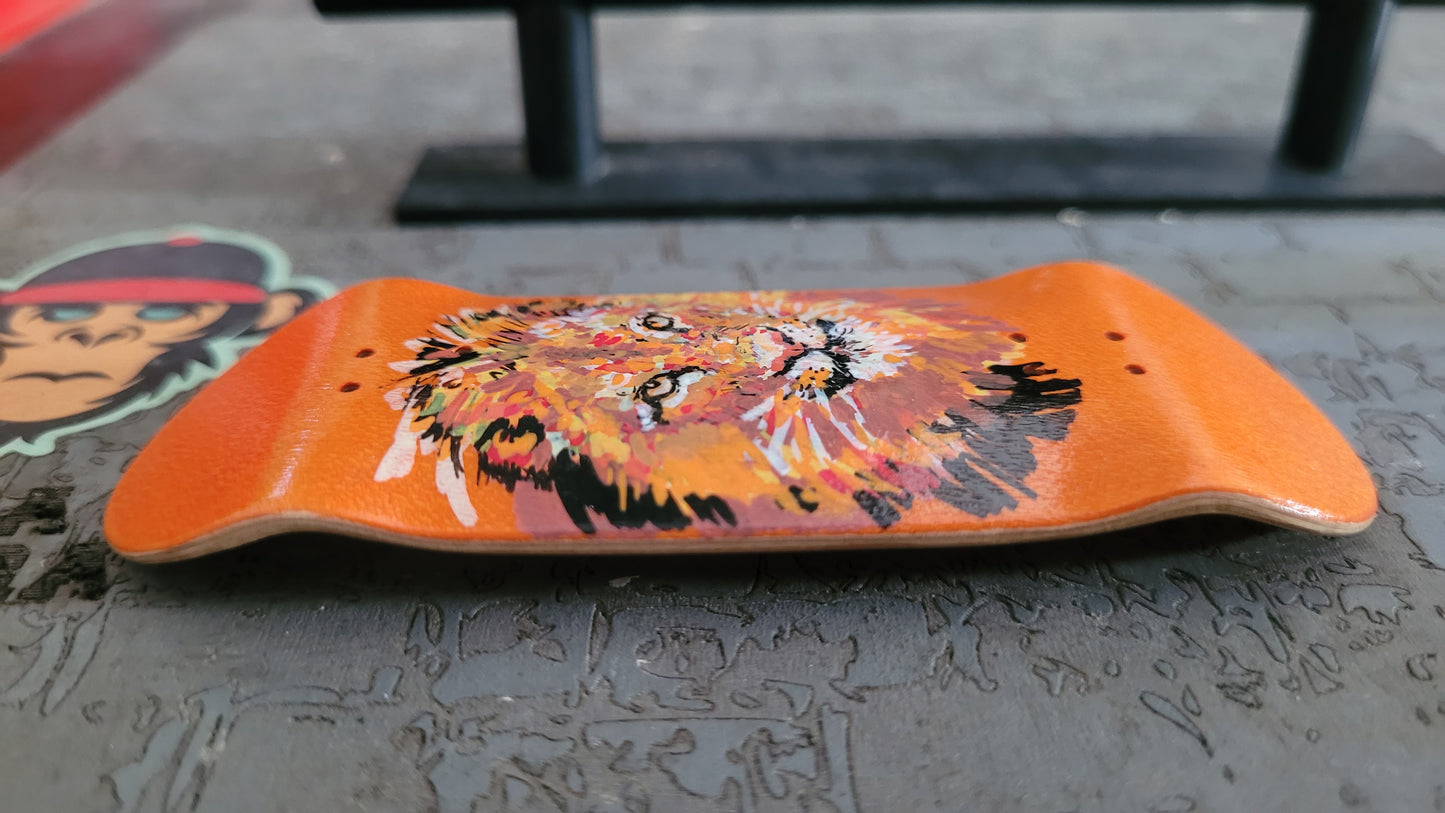 Orange fingerboard deck with lion design on a concrete surface