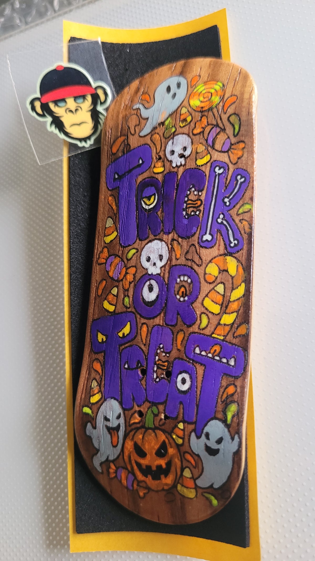 Skateboard deck in packaging with orange “TRICK OR TREAT” Halloween graphic, ghosts and pumpkin