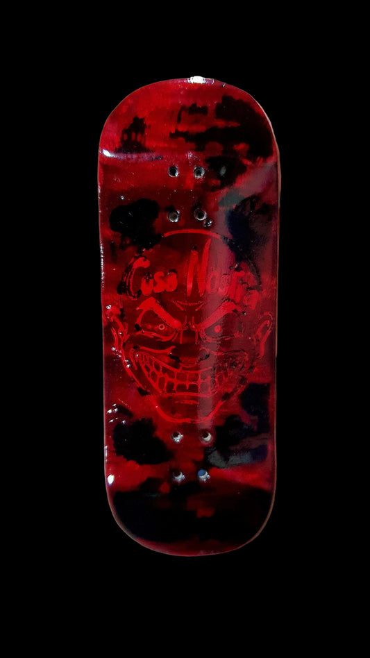 Red skateboard deck with a skull design held in a hand against a blurred background