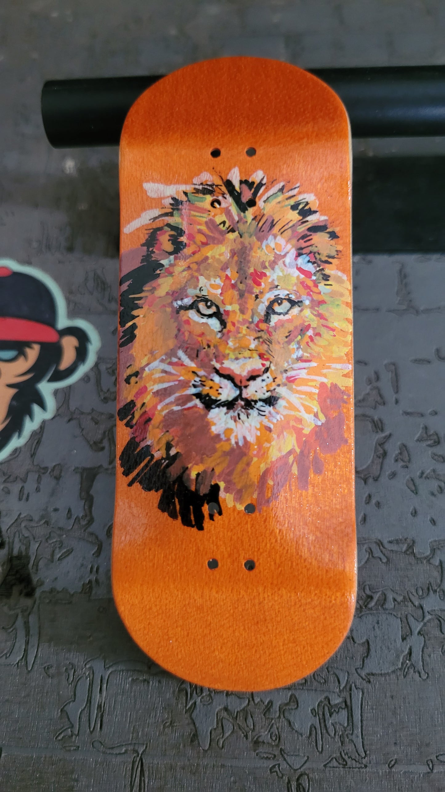 Fingerboard deck with a lion design on an orange background