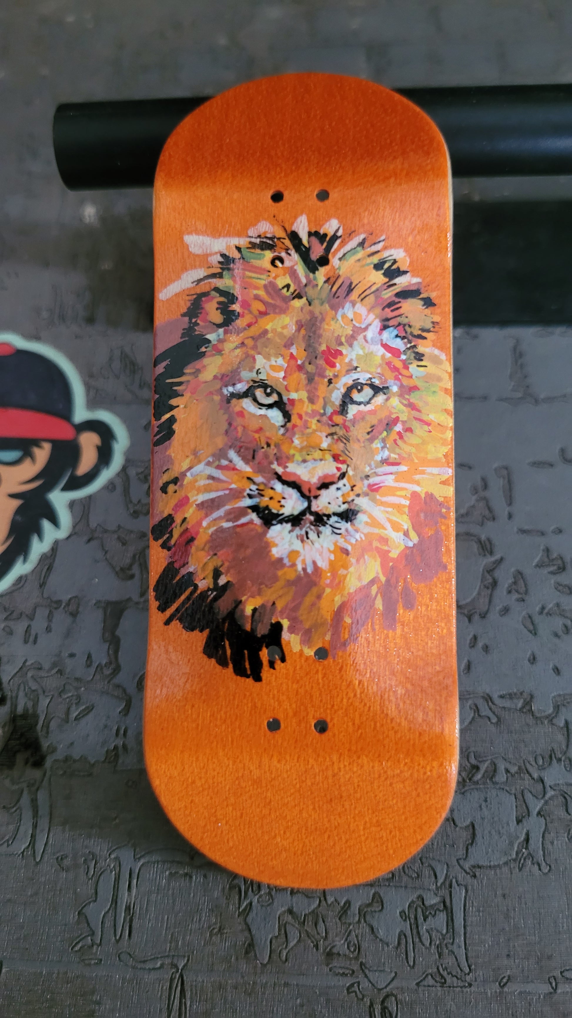 Fingerboard deck with a lion design on an orange background
