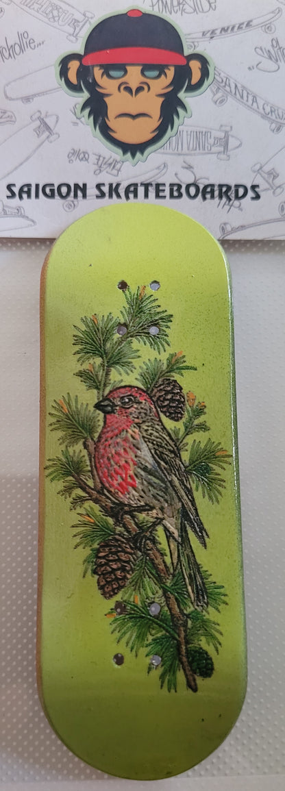 Green fingerboard deck with red bird, pine needles, and pinecone illustration