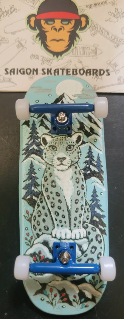 Teal finger skateboard with snow leopard graphic, blue trucks and four white wheels