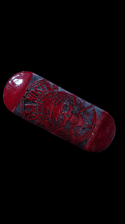 Red fingerboard deck angled view with dark central panel and skull logo