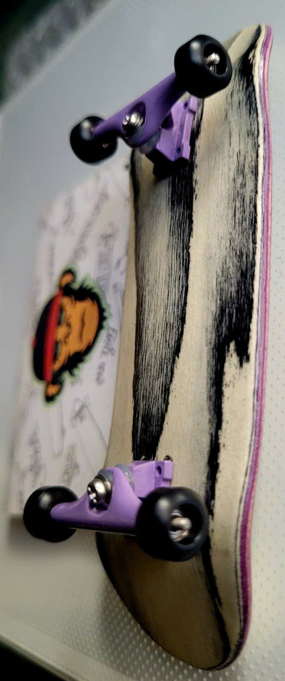 Fingerboard with black-streaked pale wood deck, purple trucks, and black wheels