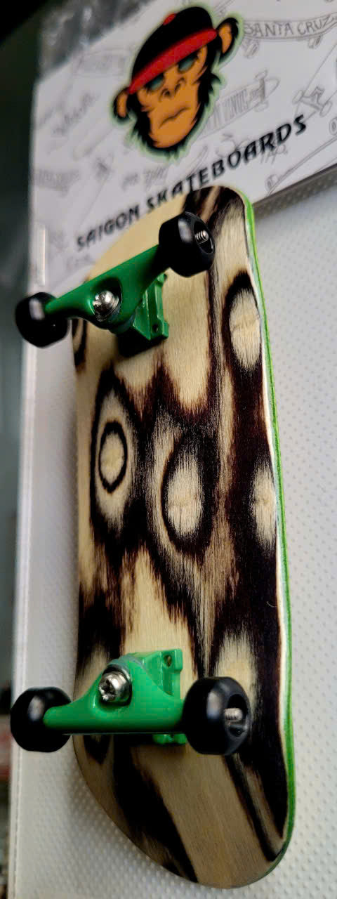 Fingerboard with dark ring-patterned deck, green trucks, and black wheels