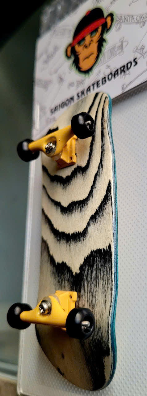 Fingerboard with black-and-cream wavy deck pattern, yellow trucks, and black wheels